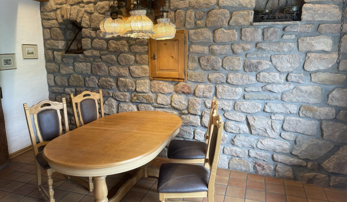 Gemütlicher Essbereich mit massivem Holztisch und Natursteinwand im Ferienhaus an der Mosel